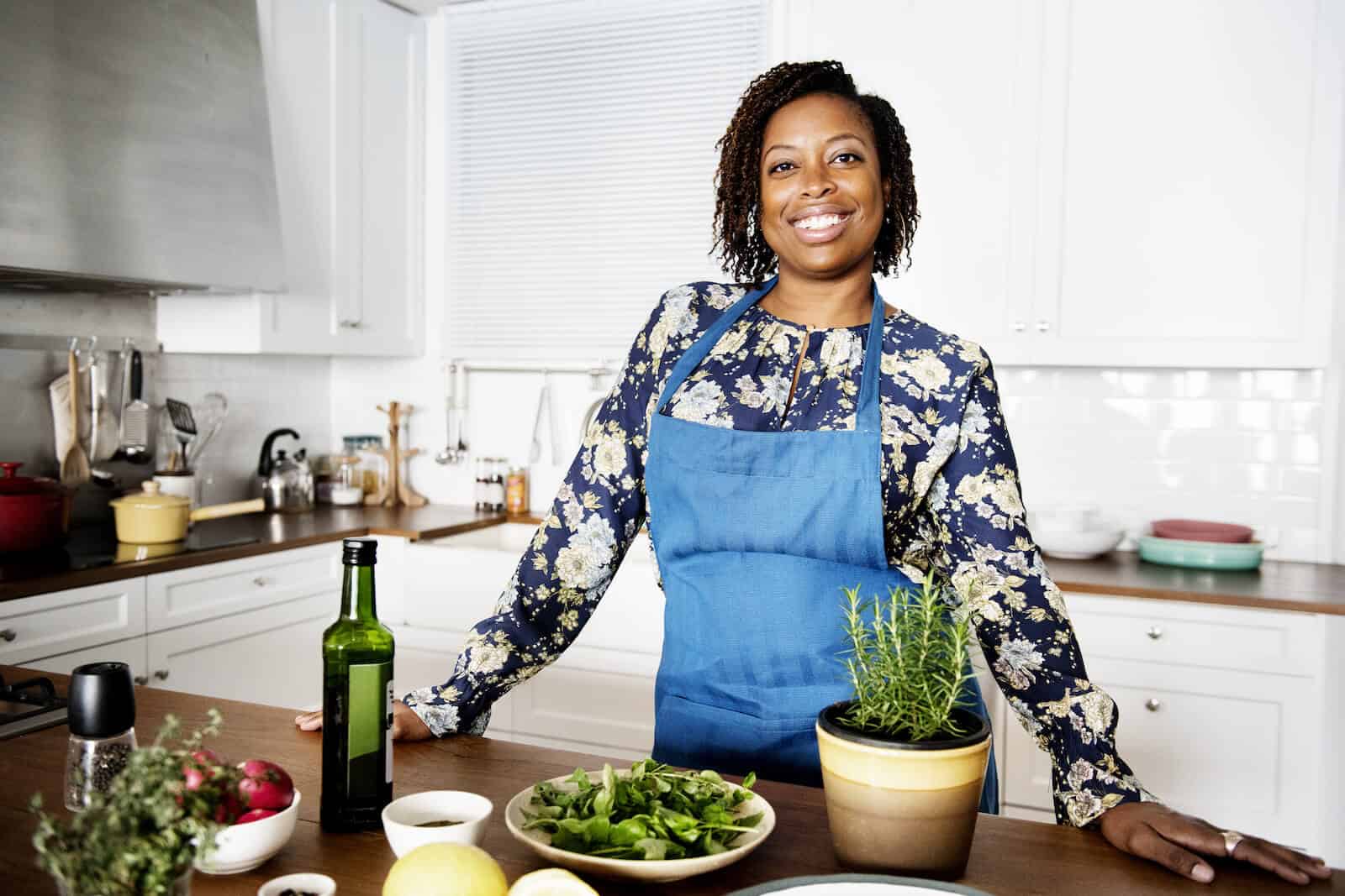 PCOS diet: happy woman preparing food in her kitchen